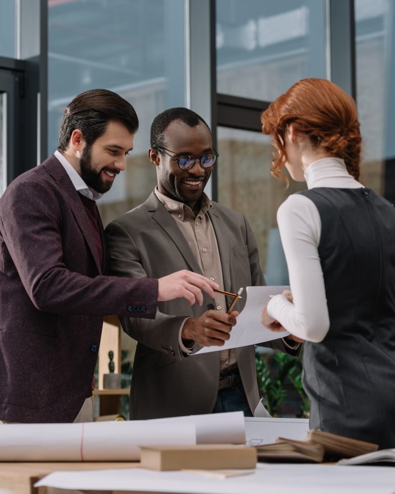 happy-multiethnic-team-of-architects-discussing-documets-at-office.jpg